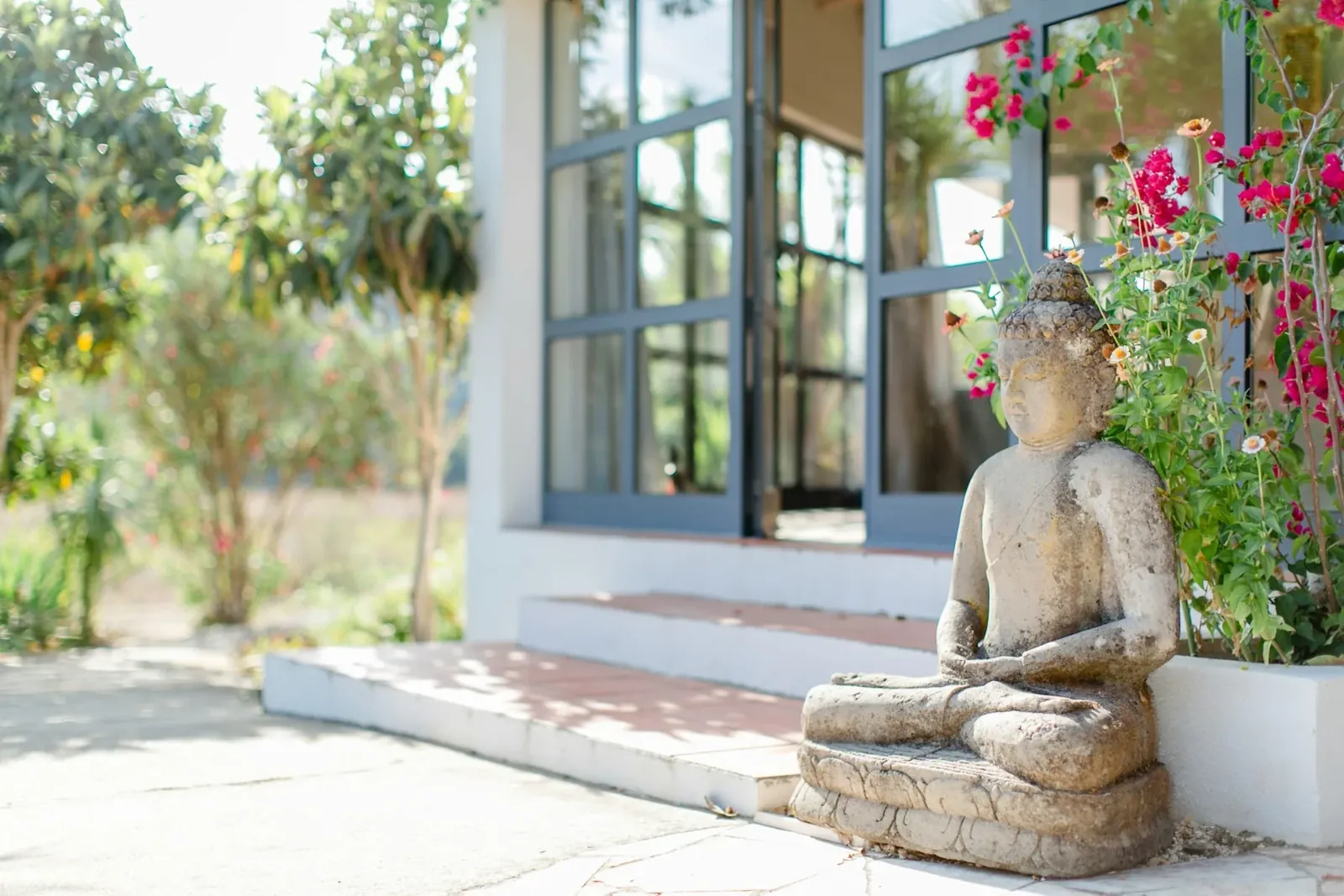 Ruhiger Garten mit Buddha-Statue als Inspiration für Ayurveda- und Gesundheitsreisen